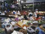The floating market in rural Thailand outside of Bangkok at rush hour. Here the locals fill their boats with whatever they produce, and trade and sell among each other and those on the shore.